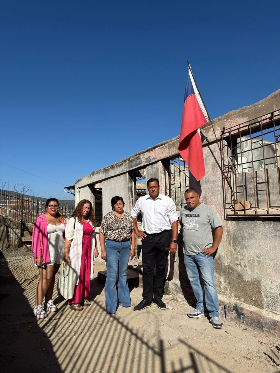 Hotuiti Teao junto a vecinas y vecinos frente a una vivienda afectada, con bandera chilena